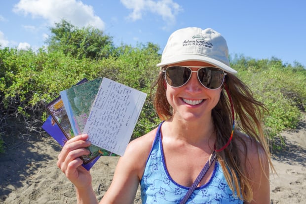 A young woman smiling and holding postcards in the Galapagos