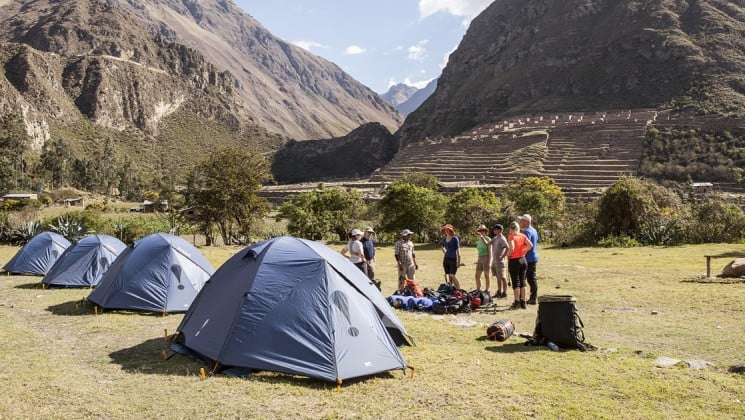 hikers set up tents at the bottom of incan ruins in peru