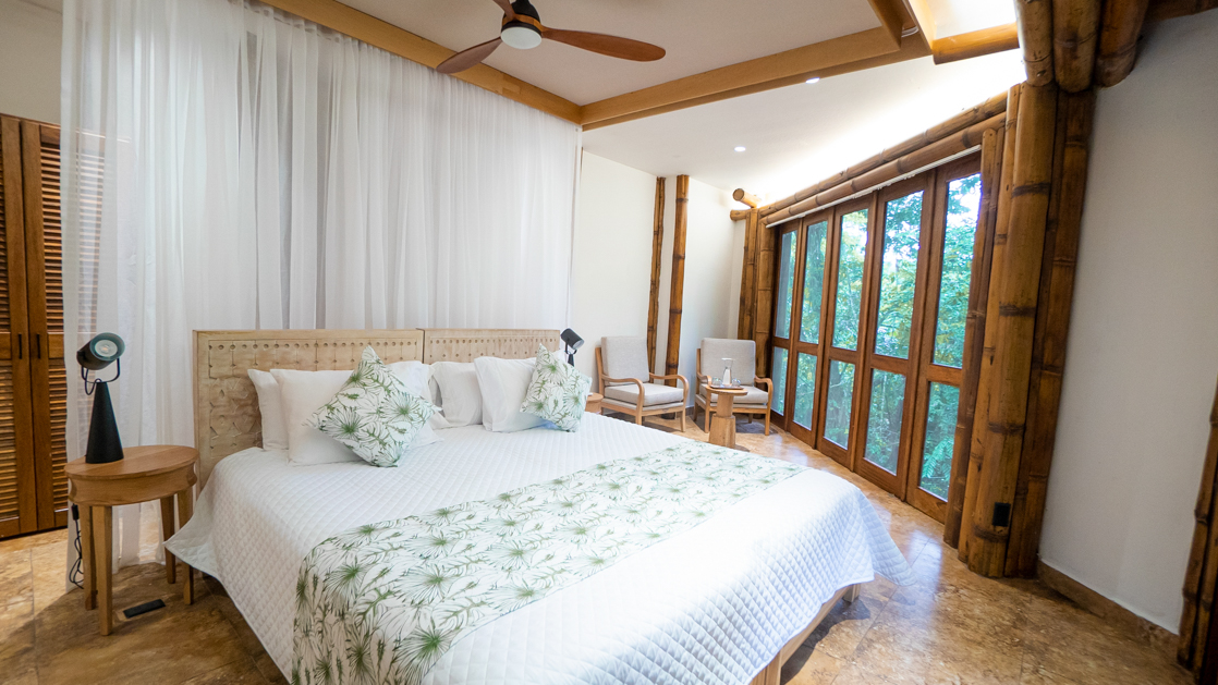 A large superior stateroom at La Selva Ecolodge with a king bed a large bay of windows looking out to the jungle in Ecuador