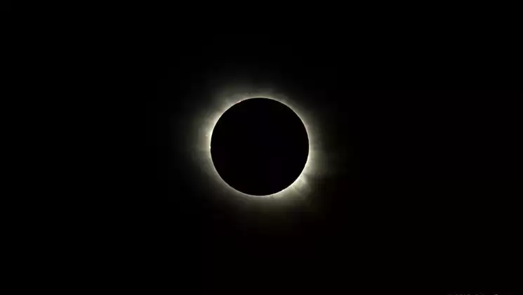 Total solar eclipse with black sky & black moon ringed with small amount of golden light.