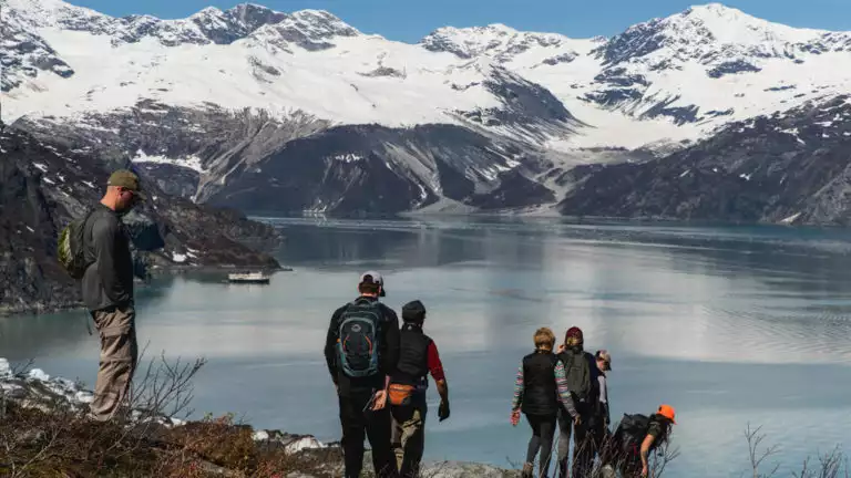Guests Hiking Lamplugh in Glacier Bay witha view of a fjord with a glacier.