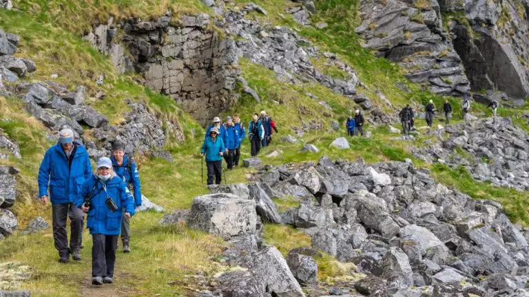 Lindblad Expeditions guests on a hike in the summer only former fishing village of Mastad, on the island of Vaeroya, Norway.