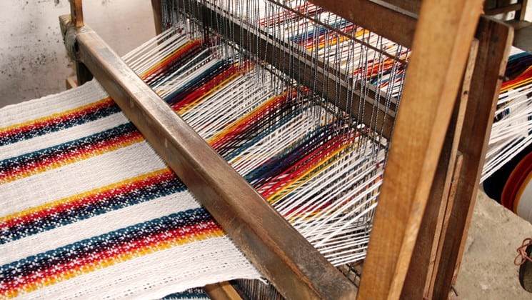 large tapestry being woven on loom on otavalo escape ecuador land tour