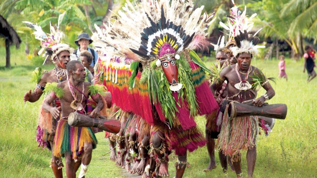 Local men perform a tribal dance with a large headdress & wooden drums, seen on a Frontier Lands of Papua New Guinea cruise.
