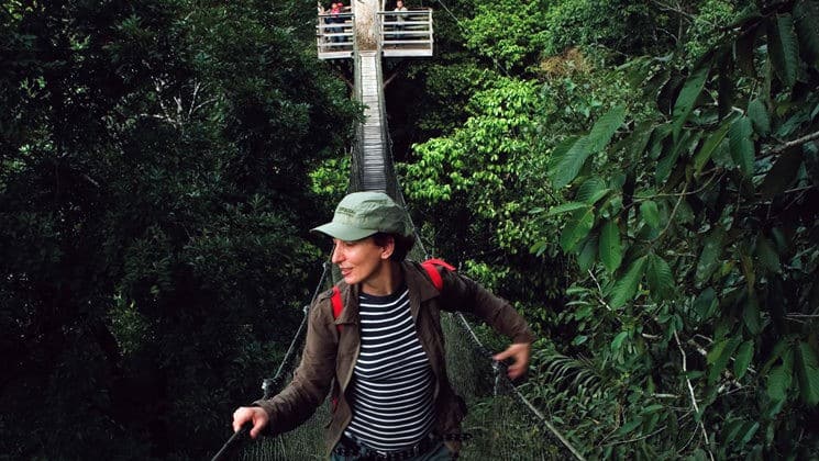 female solo traveler walking through the amazon jungle canopy on a land tour