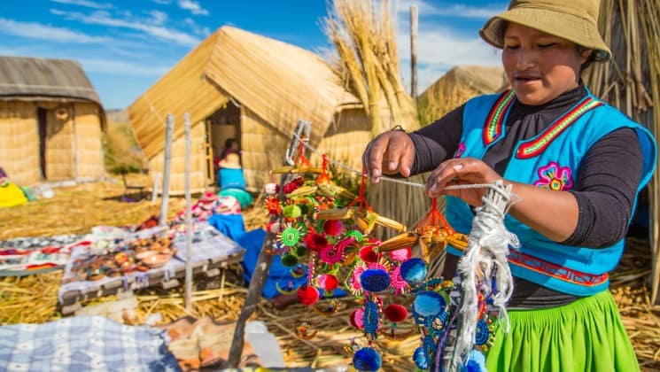 peruvian woman in colorful clothing hangs crafts at market on peru highlights trip