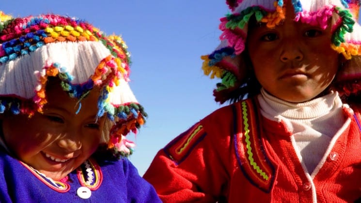 two local children in colorful hats on puno & lake titicaca land tour in peru