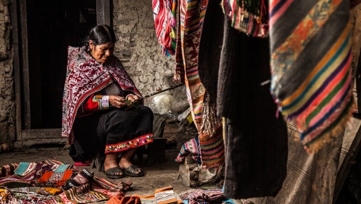 a peruvian woman sits and weaves on sacred valley & lares adventure to machu picchu land tour