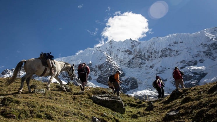 several hikers and a horse approach ridge on salkantay trek to machu picchu