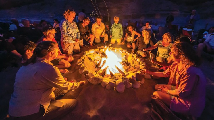 Baja travelers roast marshmallows by campfire at dusk on the From Southern California to Baja: Sailing the Pacific Coast cruise.