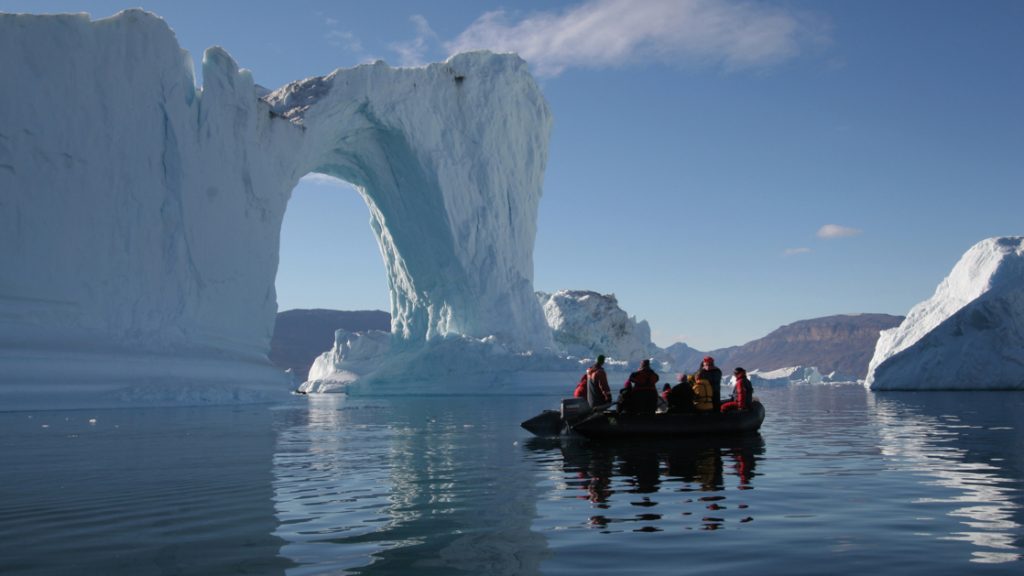 A zodiac cruises through the waters off Spitsbergen northeast Greenland surrounded by ice which forms an arch formation