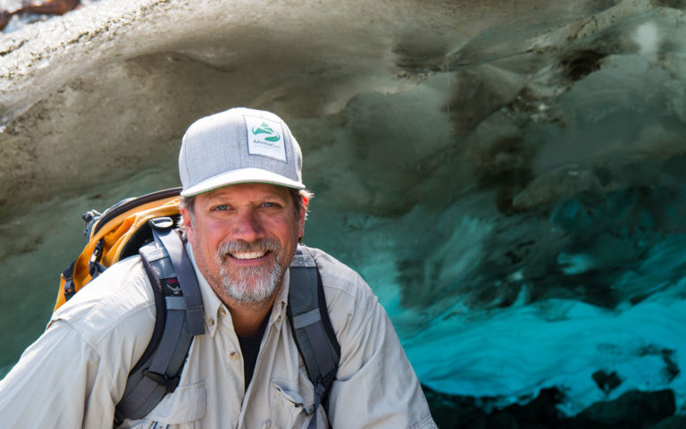 adventuresmith explorations president and founder todd smith sitting in front of a glacier in alaska smiling