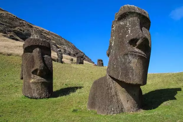 Two Moai statues in Easter Island, Chile with green grass and blue skies.