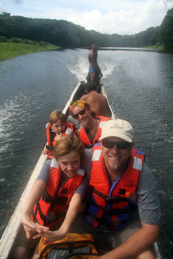 Family of travelers in a traditional wood carved motorized canoe on a river in Panama.