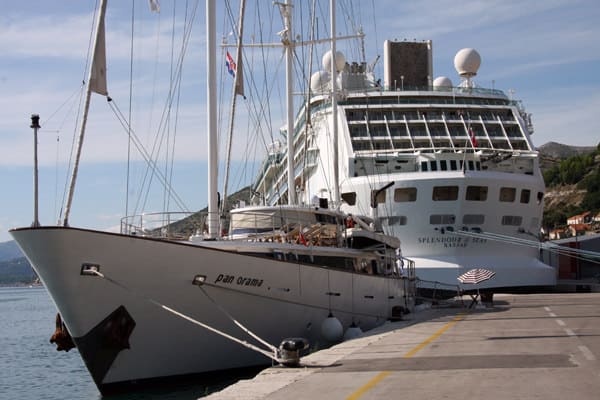 Panorama small ship docked in port of Dubrovnik Croatia next to a larger cruise ship. 