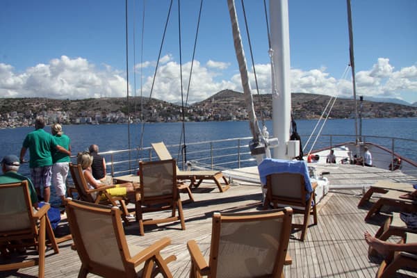 People lounging on the bow of their small ship cruising the Adriatic sea. 