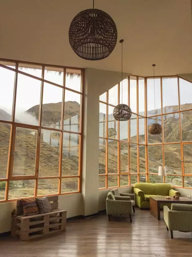 View of a lobby in a lodge with large windows looking a large mountain hillsides.