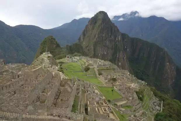 View looking down of Machu Picchu with large mountains surrounding the ruin.