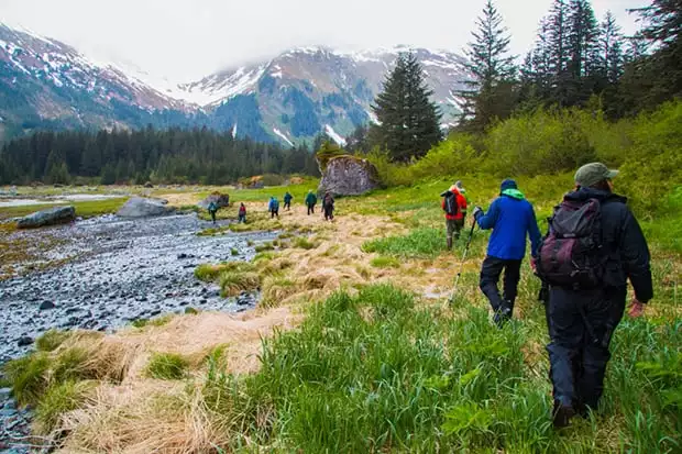 A group of Alaska travelers hiking along a creek.