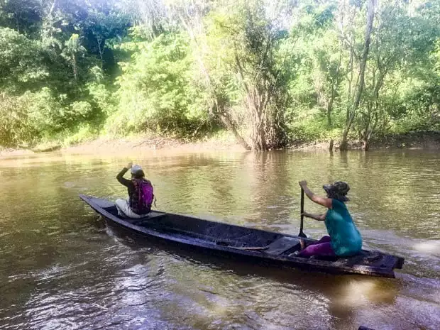 Two women paddling a canoe in the Peruvian Amazon river. 