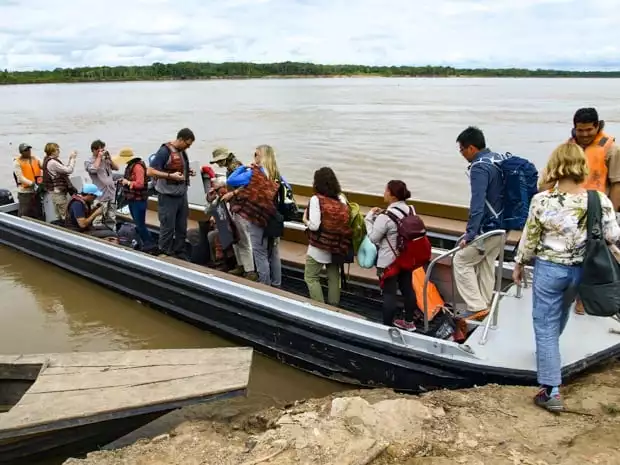 A group of people boarding a motorized canoe on the Peruvian Amazon jungle. 