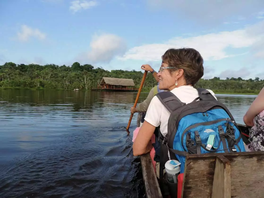 Travelers in a wooden canoe viewing the Amazon jungle from the water.