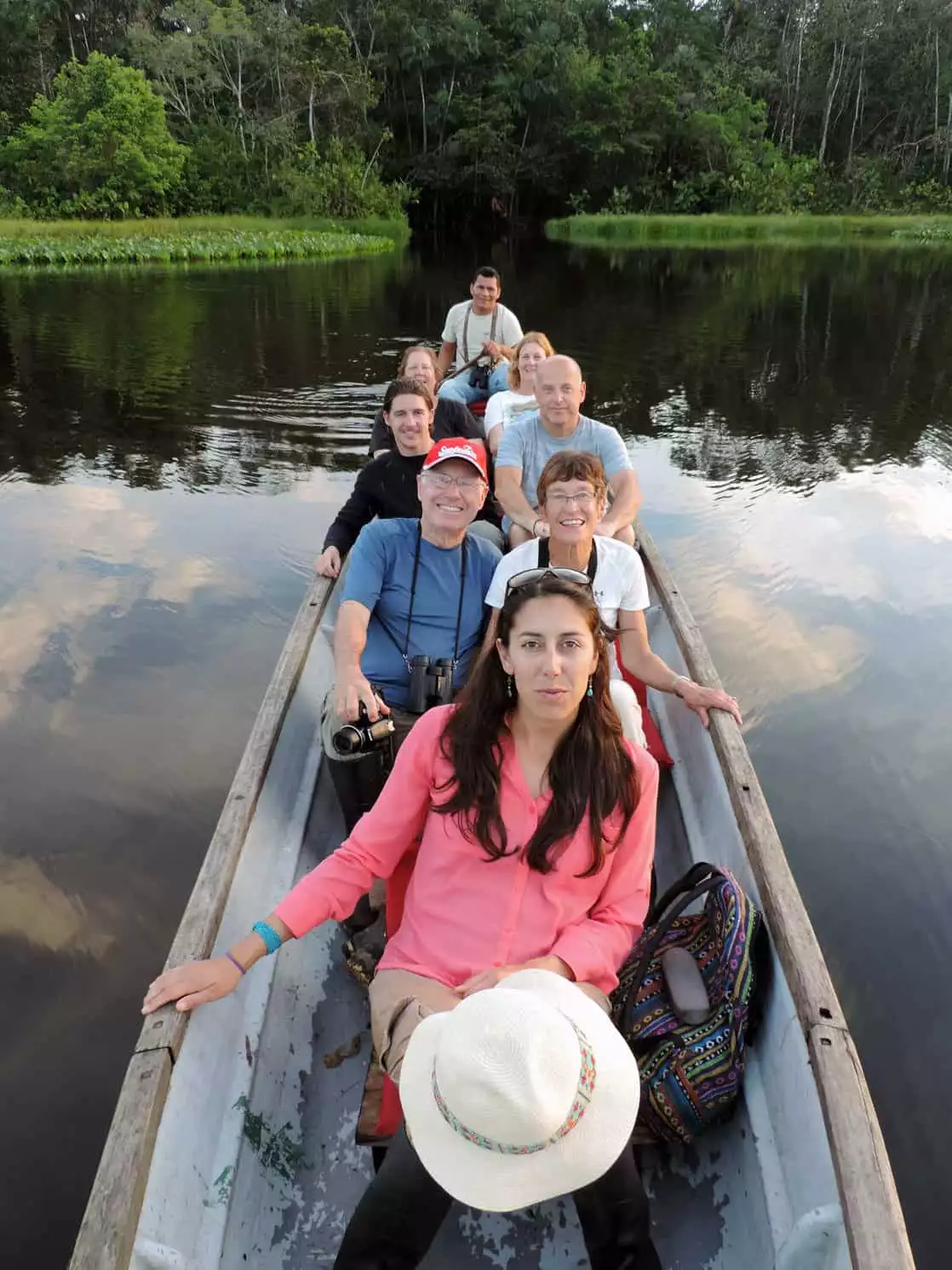 A group of Amazon travelers in a wooden canoe floating on a river in the Amazon.