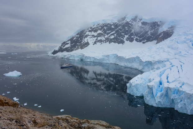 View from a hike of the ice shelf in Antarctica with small ship in the bay. 