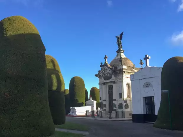 Cemetery in Punta Arenas, Chile with a mausoleum surrounded by tall landscaped trees.  