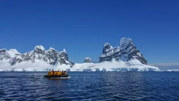 Guests from a small ship on a skiff tour going to land in Antarctica. 