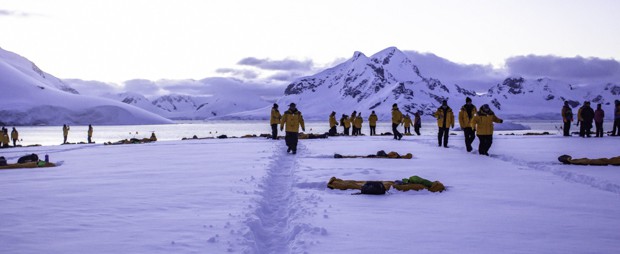 People walking in the pathway created in the snow on Antarctica to get around their campsite for the night.