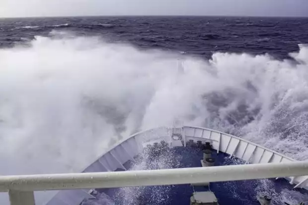 The rough seas splashing over the bow of a small cruise expedition ship during the Drake Passage returning from Antarctica. 