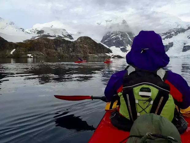 Guests from small ship cruise kayaking close to land in Antarctica. 
