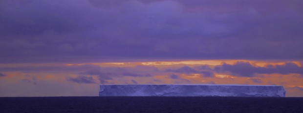 Tabular iceberg with the sunset in Antarctica, seen from a small ship cruise. 