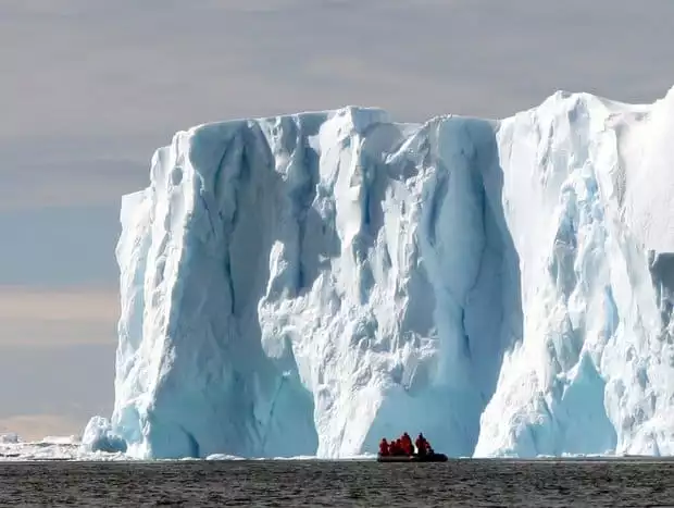 Guests off a small ship cruise on a skiff excursion in front of a massive glacier in Antarctica. 