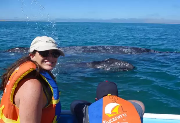 A happy couple observing 2 gray whales from the side of a panga boat.