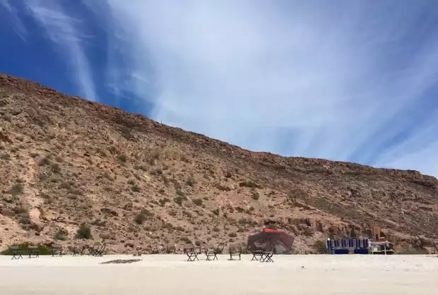 Sandy beach with chairs, tables set up on a Baja Island.