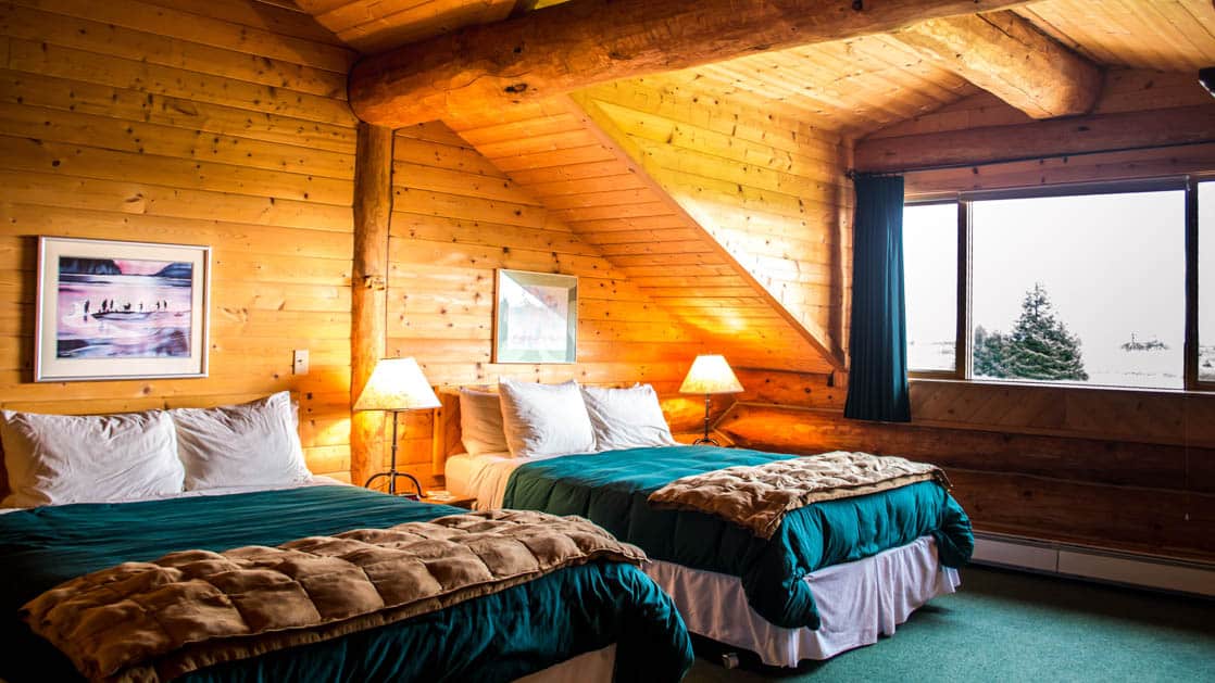 Bear Track Inn guest room in log cabin with two large beds and big window.