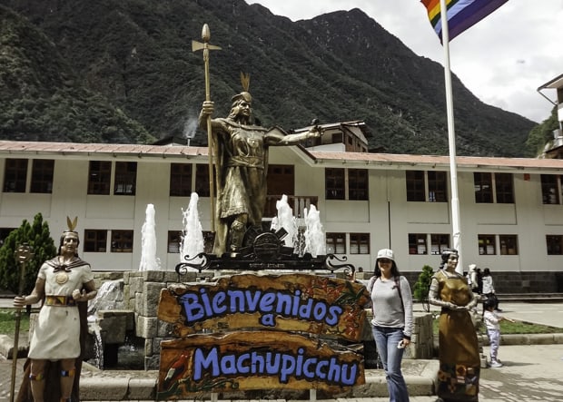 Happy guest on tour to Machu Picchu standing next to the Bienvenidos sign. 