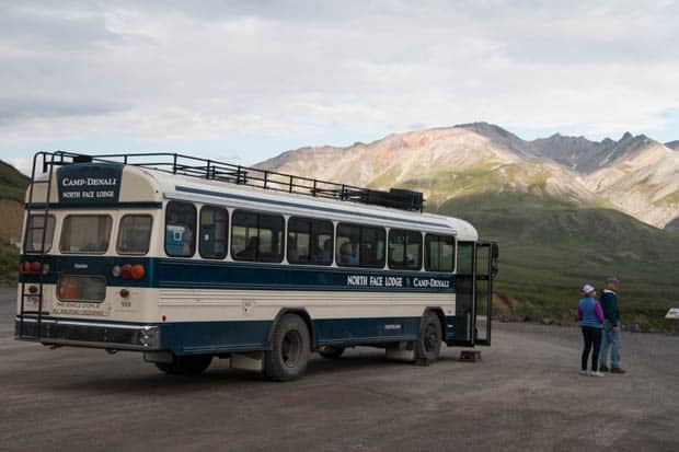 A stopped bus with people aboard and waiting to get on. 