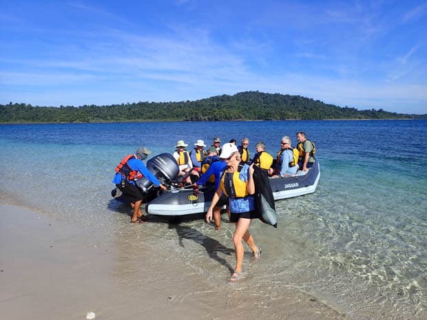 Guests getting off a skiff and onto a beach on a tour from a small ship Costa Rica and Panama cruise. 