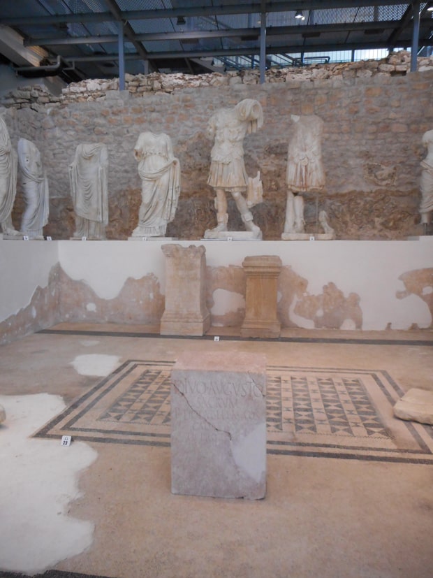 Ruin with Roman statues displayed out on a wall.