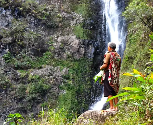 Hawaiian man standing in front of a waterfall