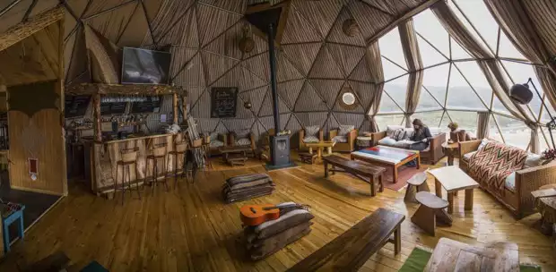 View of the lobby in the dome of the EcoCamp with couches, chairs, tables and bar looking out into the valley of Patagonia.