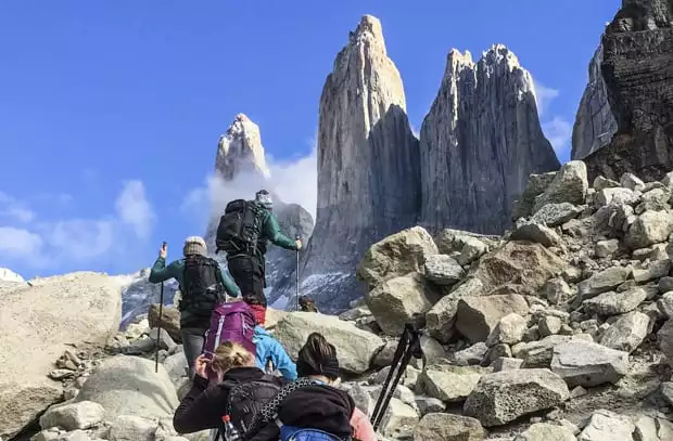 Travelers hiking up a rocky trail to 3 rock spires on a Torres del Paine Patogonian land tour.