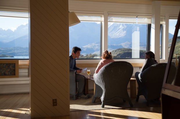 Travelers enjoying time in the Explora Lodge while enjoying the panoramic view of the mountains of Torres del Paine National Park.