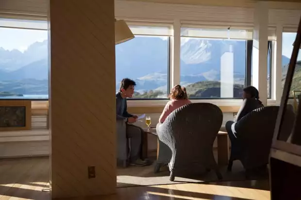 Travelers enjoying time in the Explora Lodge while enjoying the panoramic view of the mountains of Torres del Paine National Park.