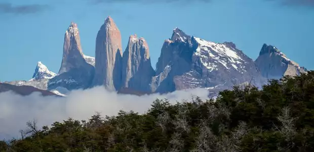 Landscape view of granite rock towers and mountains amongst the forest in Torres del Paine National Park on a Patogonia land tour.