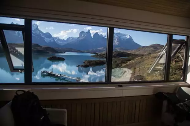 Panoramic view from a window at Explora Lodge of Lake Pehoe and snowcapped mountains in Patagonia's Torres del Paine National Park.