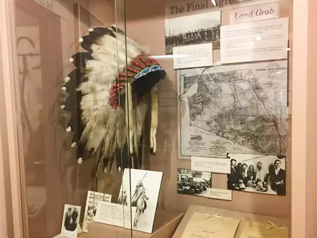 A glass showcase at the Nez Perce county Historical Society museum showing a native american headdress and old pictures. 